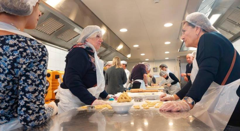 Dans le restaurant scolaire du boulevard des Promenades à Carouge, les bénévoles ont enfilé  des tabliers pour s’activer à la préparation de près de 6000 biscuits. TR